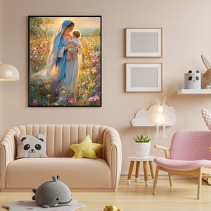 May include: A framed artwork depicts a woman in a blue robe holding a child in a field of flowers. The room features a pink sofa with decorative pillows, a pink chair, and a small side table with a plant. Two framed blank pictures are on the wall.