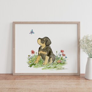 May include: Watercolor painting of a brown and black puppy sitting in a field of flowers. The puppy is looking up at a blue dragonfly. The painting is signed "Debra L. Bowman".