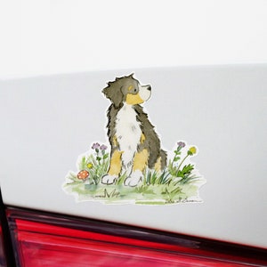 May include: A watercolor illustration of a Bernese Mountain Dog sitting in a field of wildflowers. The dog is looking up and has a brown, black, and white coat. The background is a light blue sky.