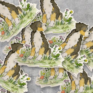 May include: A set of six colorful stickers featuring a Bernese Mountain Dog puppy in various poses. Each sticker has a watercolor-like style and includes a green background with flowers and mushrooms.
