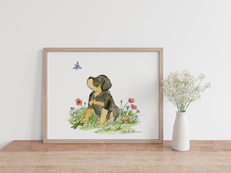 May include: Watercolor painting of a brown and black puppy sitting in a field of flowers. The puppy is looking up at a blue dragonfly. The painting is signed "Debra L. Bowman".