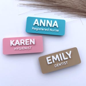 Puede incluir: Tres insignias rectangulares con nombres en verde azulado, rosa y marrón claro. Cada insignia tiene un nombre y un título blancos impresos en 3D: "ANNA Registered Nurse", "KAREN Hygienist" y "EMILY Dentist".