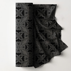 May include: A rolled-up fabric with a repeating black pattern on a gray background. The pattern features bat and skull motifs within a swirling, gothic design. The fabric is partially unrolled, revealing the detailed design.