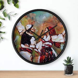 Könnte beinhalten: Eine runde Wanduhr mit schwarzem Rahmen. Das Zifferblatt zeigt ein farbenfrohes Gemälde von zwei Personen in traditioneller Kleidung beim Tanzen. Das Gemälde hat einen strukturierten Pinselstrichstil mit roten, weißen und schwarzen Akzenten.