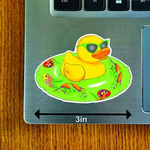 May include: A 3-inch sticker featuring a yellow duck wearing green sunglasses, floating in a green inner tube decorated with colorful sea creatures. The sticker is on a laptop.