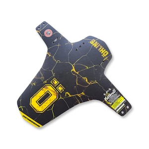 May include: Black and yellow mountain bike fender with a cracked pattern design. The fender has the word "ÖHLINS" printed in yellow, along with the "O" logo and the words "CUSTOM MUDGUARD".