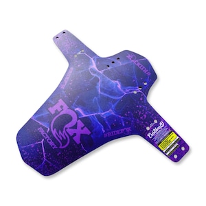 Peut inclure: Un garde-boue de vélo violet et bleu avec un motif d'éclair. Le garde-boue présente le logo "FOX FACTORY" et le texte "#RIDEFOX". Le produit est de la marque Custom D.