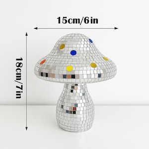 Pu&ograve; includere: Un oggetto decorativo a forma di fungo ricoperto da piccole piastrelle a specchio riflettenti. Il fungo &egrave; alto 18 cm e largo 15 cm, con accenti colorati.