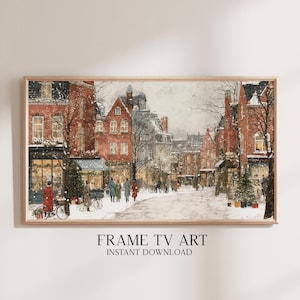Puede incluir: Una impresión en acuarela enmarcada de una escena de calle europea nevada. Edificios de ladrillo rojo bordean la calle, con tiendas y peatones visibles. El texto "FRAME TV ART INSTANT DOWNLOAD" está en la parte inferior.