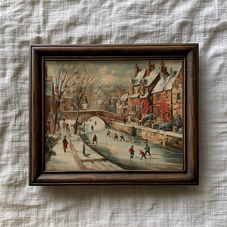 May include: A framed vintage painting shows a winter scene with a bridge, buildings, and figures ice skating. The artwork has a brown wooden frame and a muted colour palette, with snow-covered rooftops and a frozen waterway.