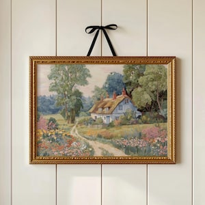 May include: A framed landscape painting of a cottage with a thatched roof, surrounded by trees and flowers. The painting has a gold ornate frame and is suspended by a black ribbon. The artwork depicts a serene countryside scene.