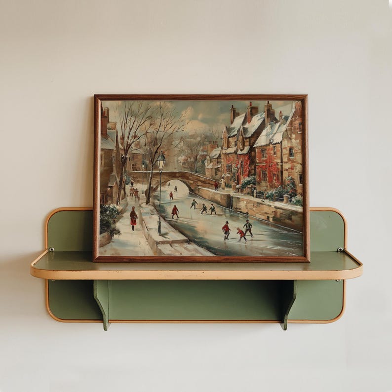 May include: A framed vintage painting showing a winter scene with people ice skating on a frozen river. The artwork, in a brown wooden frame, is displayed on a green and beige shelf. The painting features a bridge and buildings.