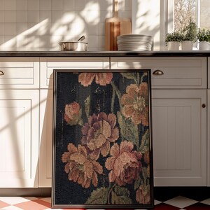 Puede incluir: Un tapiz floral enmarcado con grandes flores estilizadas en tonos melocot&oacute;n, rosa y verde sobre un fondo azul oscuro. El tapiz se exhibe sobre un suelo a cuadros rojos y blancos en un entorno de cocina.