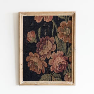 Puede incluir: Un tapiz floral enmarcado con grandes flores detalladas en tonos melocot&oacute;n, marr&oacute;n y verde sobre un fondo oscuro. La obra de arte est&aacute; encerrada en un marco de madera de color claro, creando una est&eacute;tica vintage.