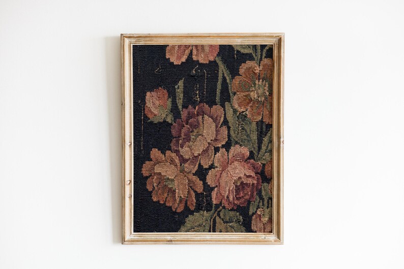 Puede incluir: Un tapiz floral enmarcado con grandes flores detalladas en tonos melocot&oacute;n, marr&oacute;n y verde sobre un fondo oscuro. La obra de arte est&aacute; encerrada en un marco de madera de color claro, creando una est&eacute;tica vintage.