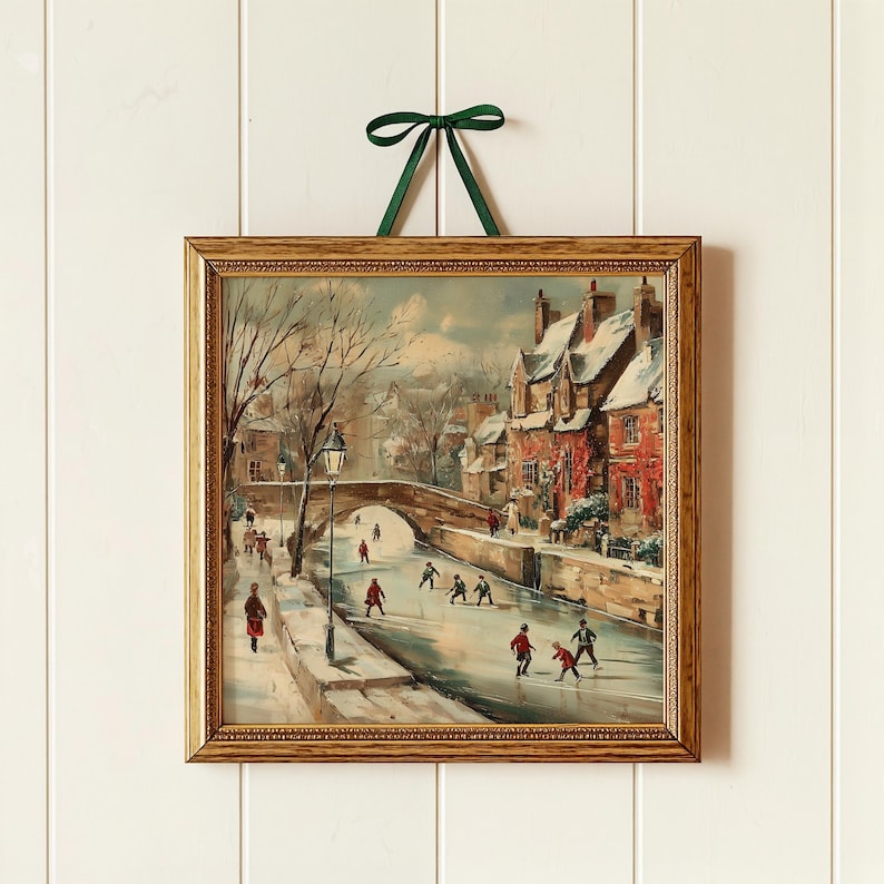 May include: A framed painting of a winter scene with people ice skating on a frozen river. The artwork shows a bridge, buildings with red walls, and bare trees. The frame is gold, and a green ribbon is attached for hanging. The painting is in a gold frame.