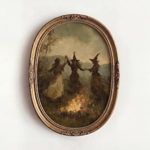 Op de afbeelding: Een ovaalvormig wandkunstwerk met een schilderij van drie figuren met puntmutsen die rond een kampvuur in een veld dansen. Het kunstwerk is gevat in een sierlijke, goudkleurige lijst met gedetailleerde reliëfversieringen langs de randen.