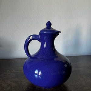 May include: A white ceramic mug with a black handle and the text "But First, Coffee" in a handwritten style. The mug is on a white surface. The mug is 4 inches tall.