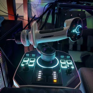 May include: A white and black gaming joystick with illuminated blue and green accents. The joystick has multiple buttons and dials, with a central control stick and a base with digital displays. The overall design is futuristic and high-tech.