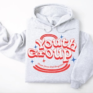 May include: Light gray hoodie with the words "Youth Group" in red and white retro font. The hoodie also has the text "Chase Jesus Not Perfection" in red. Blue star graphics are also present.