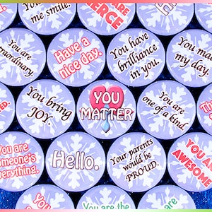 May include: A collection of colourful round buttons with positive messages, such as "You are awesome", "You bring joy", and "You matter". The buttons have a snowflake design and are on a purple background.