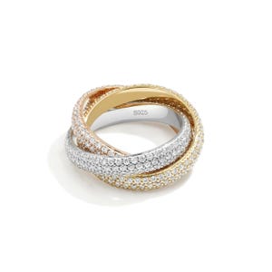 May include: A three-band ring with a gold, rose gold, and silver design. Each band is encrusted with small, sparkling stones. The ring is a modern piece of jewelry.