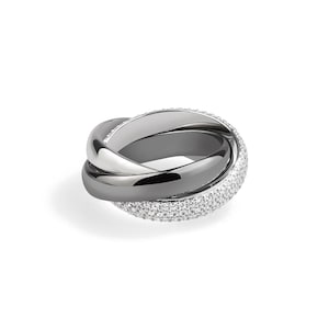 May include: A contemporary three-band ring. One band is silver, another is dark grey, and the third is set with small, sparkling crystals. The bands are interwoven, forming a distinctive and stylish design. This ring is a piece of jewellery.
