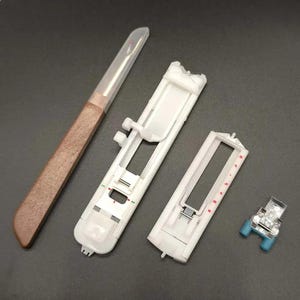 May include: A sewing kit with a seam ripper, two white plastic presser foot holders, and a small presser foot with blue accents. The seam ripper has a brown handle and a clear plastic cover.