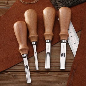 May include: Four leather working tools with wooden handles and stainless steel blades. The blades are labeled A4mm, A6mm, A8mm, and A10mm. A metal ruler is also visible, with measurements in inches.