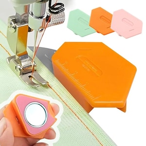May include: A magnetic sewing seam guide in orange, light green, and pink. The tool features a hexagonal shape with a built-in ruler along the edge. It is designed to attach to a sewing machine to assist with straight stitching and consistent seam widths.
