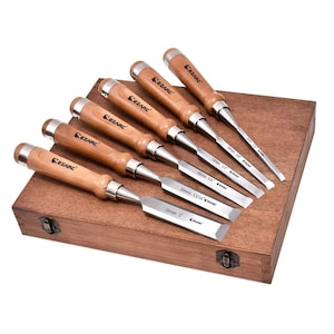 Puede incluir: Un juego de seis formones de madera con mangos de madera y hojas de metal, dispuestos en una caja de madera. Las hojas tienen medidas en milímetros. La marca "CEZARC" está impresa en los mangos.