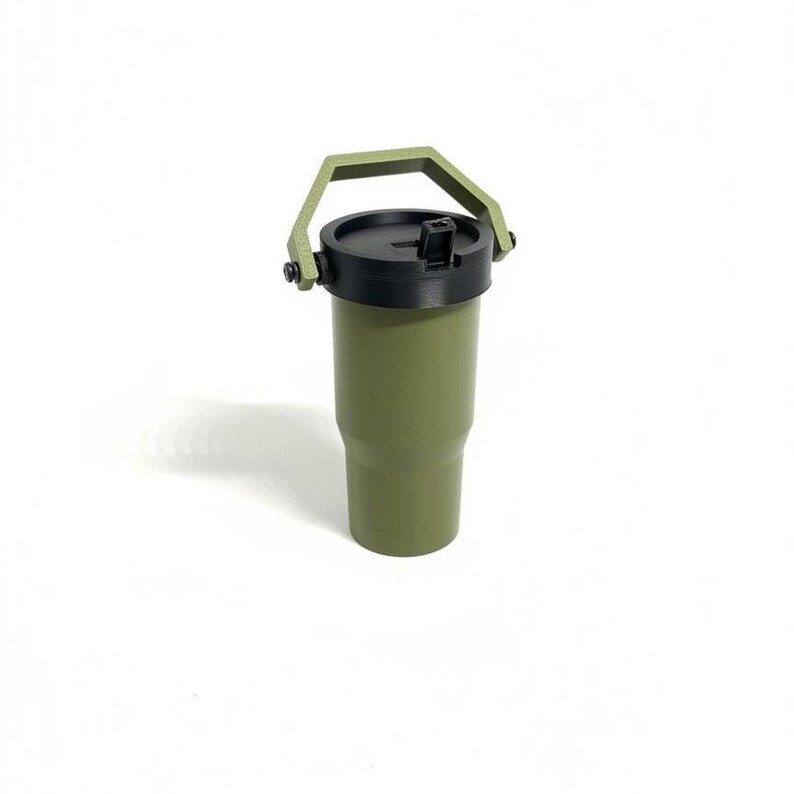 Puede incluir: Vaso t&eacute;rmico verde oliva con tapa negra y asa verde a juego. El vaso cil&iacute;ndrico tiene un asa fijada a la tapa. Dise&ntilde;ado para mantener las bebidas fr&iacute;as o calientes. Altura aproximada: 18 cm.