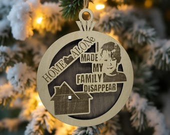 Può includere: Ornamento natalizio in legno con la scritta "HOME ALONE" e "MADE MY FAMILY DISAPPEAR". L'ornamento presenta una sagoma di casa e il volto di un bambino. È appeso a un anello di spago.