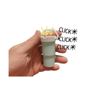 Puede incluir: Un peque&ntilde;o vaso de color verde claro con tapa y asa blancas se sostiene en una mano. El texto "CLICK" est&aacute; escrito tres veces junto al vaso. La tapa tiene una peque&ntilde;a abertura con flechas que apuntan hacia abajo.