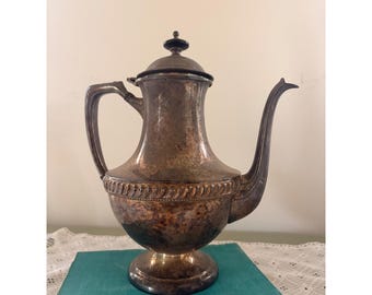 Tetera antigua de plata chapada con pátina deslustrada ornamentada y forma de media luna.