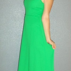 Puede incluir: Una mujer con un vestido largo, verde brillante, sin mangas y cuello alto.
