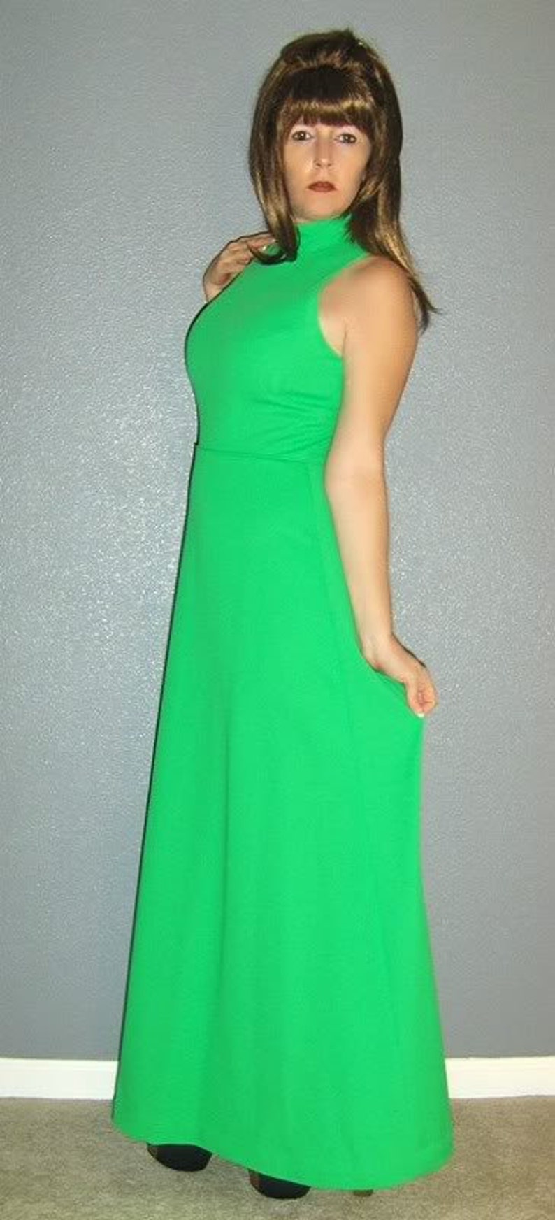 Puede incluir: Una mujer con un vestido largo, verde brillante, sin mangas y cuello alto.