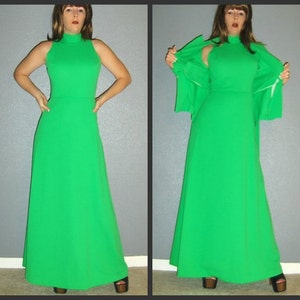Puede incluir: Un vestido largo de color verde brillante con cuello alto y sin mangas. El vestido tiene una silueta simple y elegante y est&aacute; hecho de una tela suave y fluida.