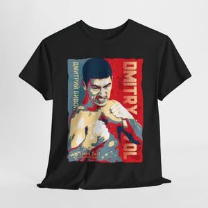 May include: Black t-shirt featuring a stylized portrait of Dmitry Bivol in a boxing pose. The design includes the name "Dmitry Bivol" in English and Cyrillic script, set against a red, blue, and yellow background.