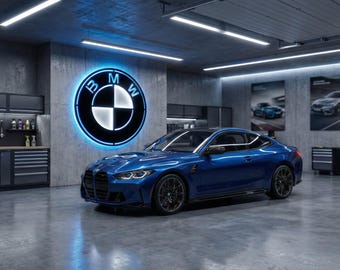 May include: A blue BMW coupe is parked in a modern garage setting. The BMW logo, illuminated, is on the wall behind the car. The garage features cabinets, tools, and posters, creating a sleek, contemporary aesthetic.