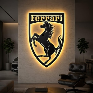 Può includere: Opera d'arte da parete con logo Ferrari in metallo nero con un emblema di cavallo rampante, illuminata da una calda luce gialla. La parola "Ferrari" è visualizzata sopra il cavallo. L'opera è montata su una parete strutturata.