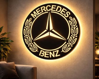 May include: A circular illuminated sign featuring the Mercedes-Benz logo. The sign has a black background with the Mercedes-Benz star emblem in the centre. The words "Mercedes" and "Benz" are displayed around the emblem in white. The sign is mounted on a wall.