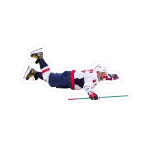 May include: A sticker depicting a hockey player in a white, navy, and red uniform, mid-air. The player is holding a hockey stick with red and green stripes. The sticker has a white border.