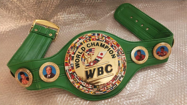 Pu&ograve; includere: Una cintura verde del campionato del World Boxing Council (WBC) con fibbia e medaglioni dorati. Il centro presenta un emblema dorato con le parole "WORLD CHAMPION" e "WBC". La cintura ha un cinturino in pelle verde.