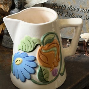 Antique or vintage ceramic pitcher with floral high relief design