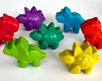 Może przedstawiać: Kolekcja kolorowych plastikowych zabawek dinozaurów w kolorze czerwonym, fioletowym, niebieskim, zielonym, żółtym i limonkowym. Zabawki ułożone są w okrąg, każda z unikalnym wzorem dinozaura.