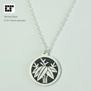 May include: Sterling silver necklace featuring a circular pendant with a black background and a white leaf design. The pendant is 0.75 inches (19mm) in diameter and hangs from a delicate silver chain. The necklace is displayed against a white background.