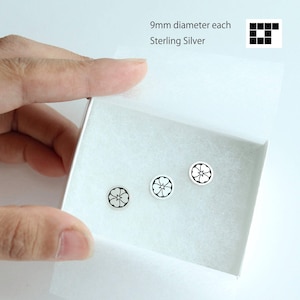 Puede incluir: Tres pendientes de botón de plata de ley, cada uno de 9 mm de diámetro, se muestran en una caja blanca. Los pendientes presentan un diseño floral en blanco y negro. El texto "9mm diameter each Sterling Silver" es visible.