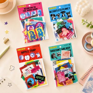 Op de afbeelding: Vier sets decoratieve papieren stickers in doorzichtige plastic verpakking. Elke set heeft een thematische kopkaart met de titel Reunion in the Dark Room, Weightless Planet, Apple Trap of Radiant Galaxy, met diverse kleurrijke grafische uitsparingen.