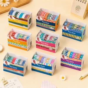 Könnte beinhalten: Sieben rechteckige Pappschachteln, die jeweils acht Rollen dekoratives Washi-Tape enthalten. Die Schachteln sind mit First Note und 8 pcs beschriftet und zeigen verschiedene bunte Muster wie Streifen, Punkte, Blumenmotive und geometrische Formen.
